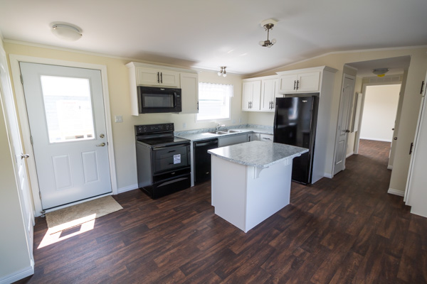 Kitchen with black appliances, island with overhang, and white cabinetry
